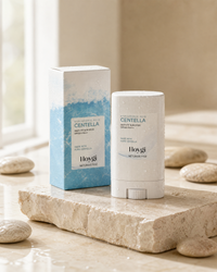 Silky-Fit Sun Stick SPF50+ on stone pedestal with water droplets